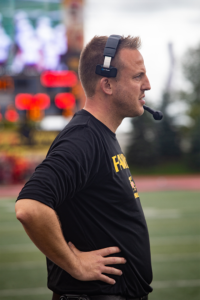 Gryphons coach stands at the sideline during homecoming game.