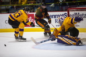 #18 Luke Kutkevicius watches the puck fly towards the Laurier net while the Laurier goalie tries to make a save.