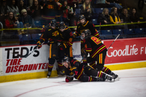 #92 Giordano Finoro falls to the ice smiling celebrating his goal.